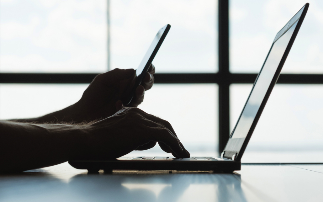 Person Looking At Phone And Laptop